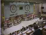 An auction room.  The prices are counting down on the clocks.  Two auctions are in progress.